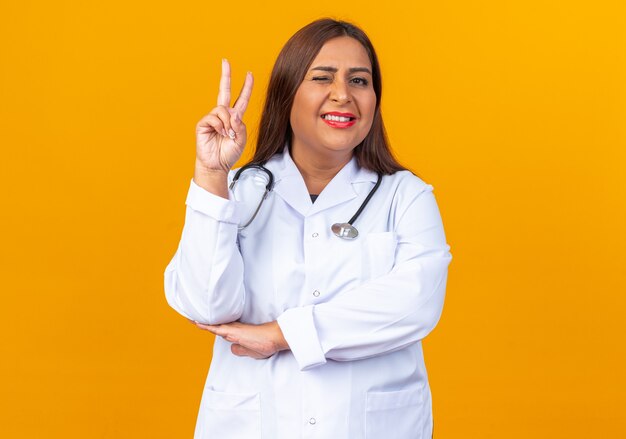 Middle age woman doctor in white coat with stethoscope looking