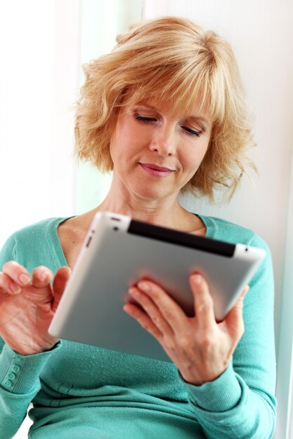 Middle age woman relaxing with tablet comper