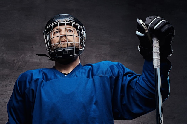 Giocatore di hockey barbuto di mezza età che indossa un'attrezzatura sportiva completa con una mazza da hockey