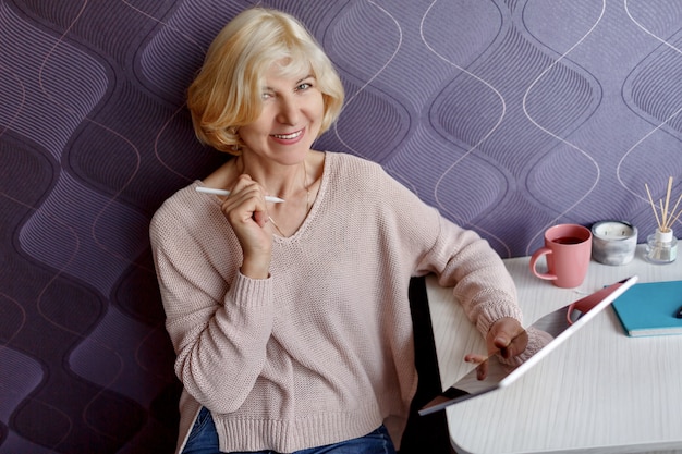 Middle aged blond woman using tablet