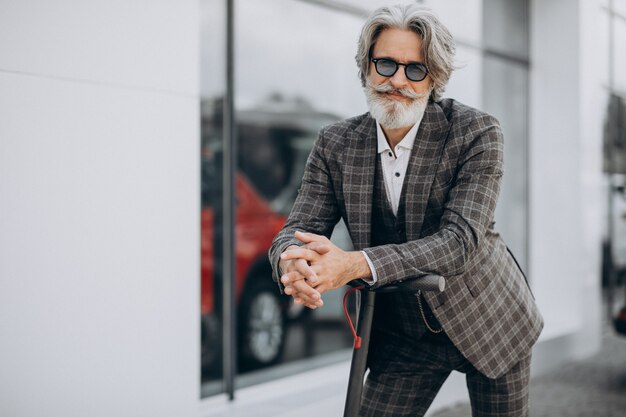 Middle aged business man riding scooter in a classy suit