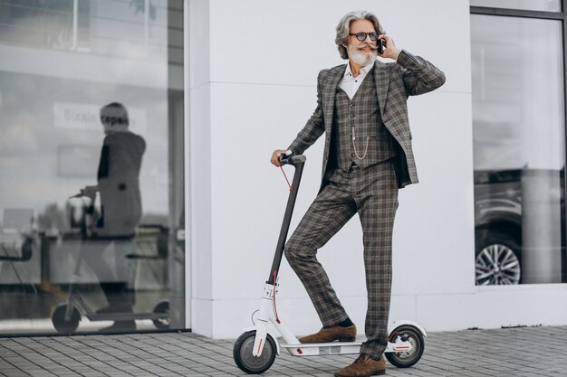 Middle aged business man riding scooter in a classy suit