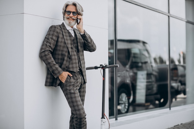 Middle aged business man riding scooter in a classy suit