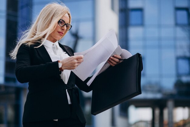 Middle aged business woman holding documents by the business center