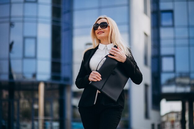 Middle aged business woman with suitcase by bussiness center