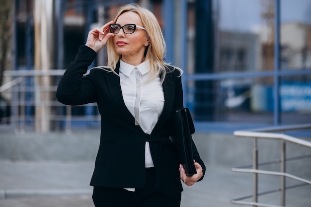 Middle aged business woman with suitcase by bussiness center