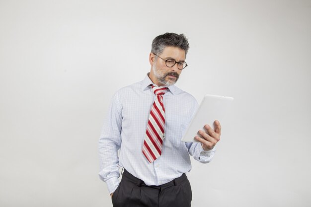 Middle-aged businessman looking at the screen on white background