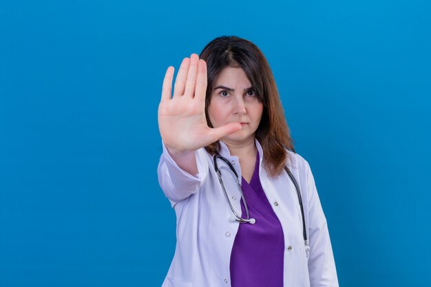 Middle aged doctor wearing white coat and with stethoscope with open hand doing stop sign with serious and confident expression