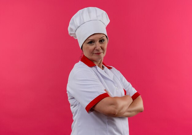  middle-aged female cook in chef uniform crossing hands on isolated pink wall with copy space