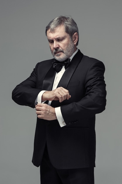 Middle aged male adult wearing a suit isolated on gray