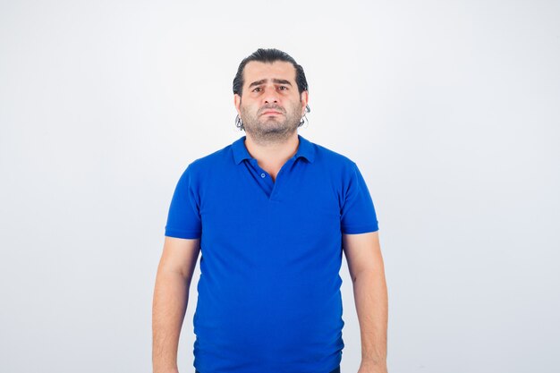 Middle aged man in blue t-shirt looking at front and looking wistful