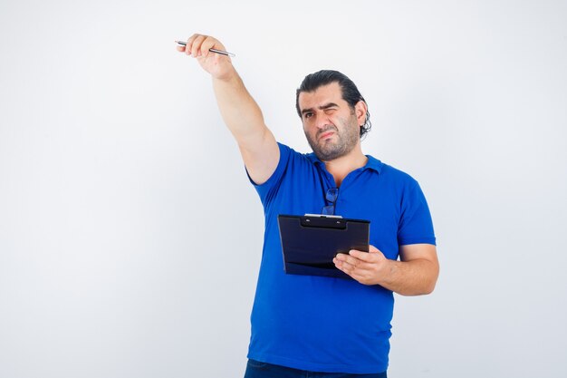 Middle aged man holding pencil and clipboard and looking focused. front view.