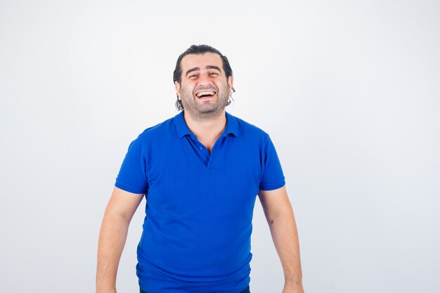 Middle aged man looking at camera in blue t-shirt and looking joyful