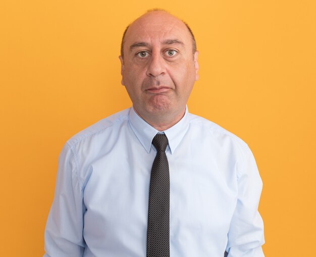 Middle-aged man looking at front wearing white t-shirt with tie isolated on orange wall