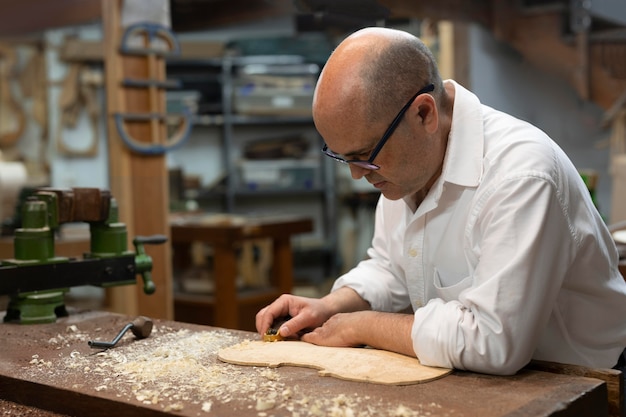 Мужчина средних лет делает инструменты в своей мастерской в одиночестве