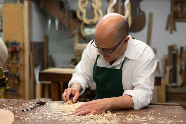 Мужчина средних лет делает инструменты в своей мастерской в одиночестве