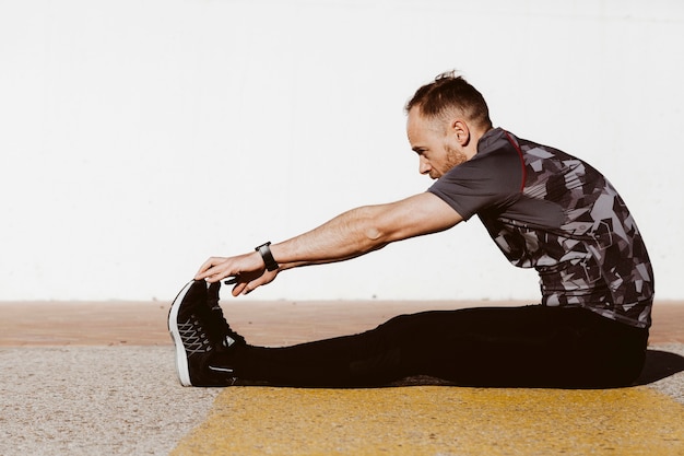 Uomo di mezza età in uniforme sportiva che si estende sul pavimento