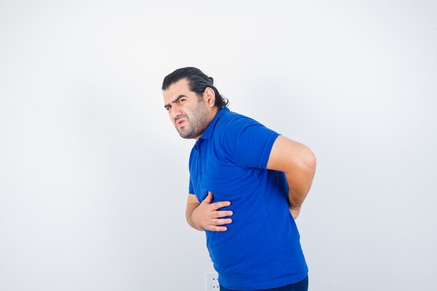 Middle aged man suffering from backache in blue t-shirt