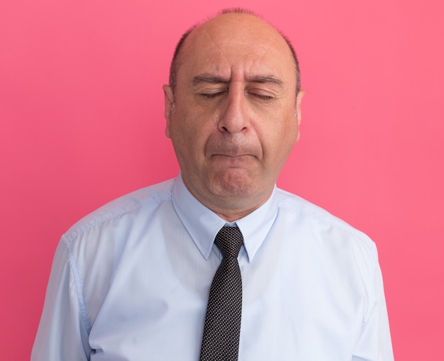 Middle-aged man with closed eyes wearing white t-shirt with tie isolated on pink wall
