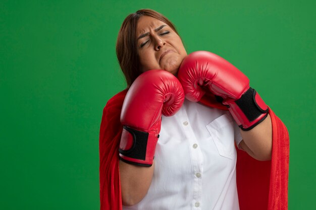 Middle-aged superhero female wearing boxing gloves - isolated on green background