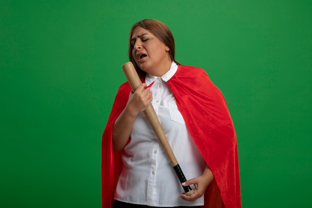 Middle-aged superhero female with closed eyes holding baseball bat and sings isolated on green