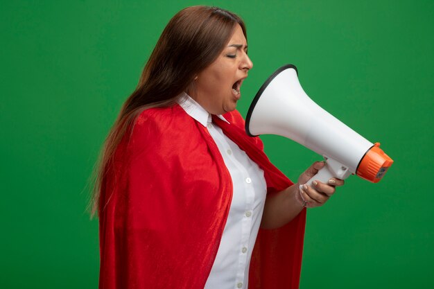 Middle-aged superhero female with closed eyes speaks on loudspeaker isolated on green