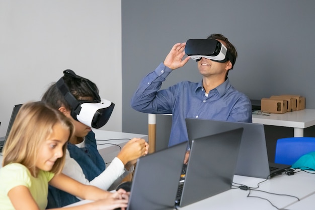 Учитель средних лет тестирует гарнитуру VR и улыбается