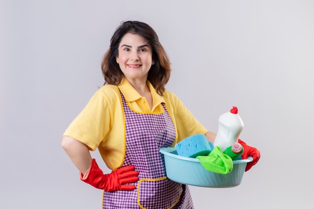 中年の女性がエプロンとゴム製の手袋を着用して洗面器を掃除用具で保持
