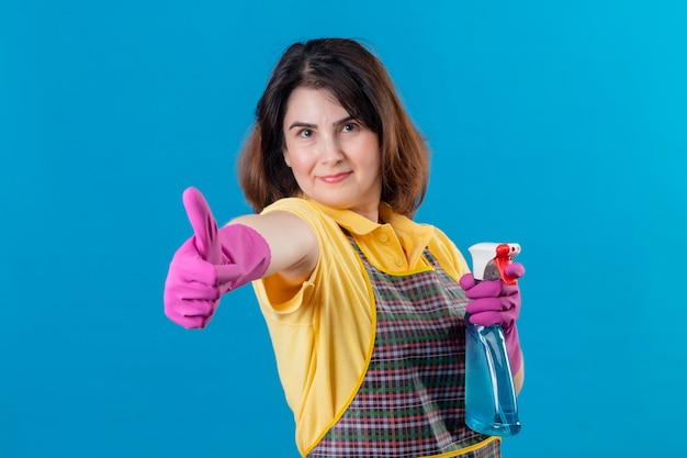 Free photo middle aged woman wearing apron and rubber gloves holding cleaning spray