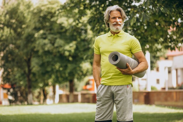 Middle aged yoga instructor with mat in park