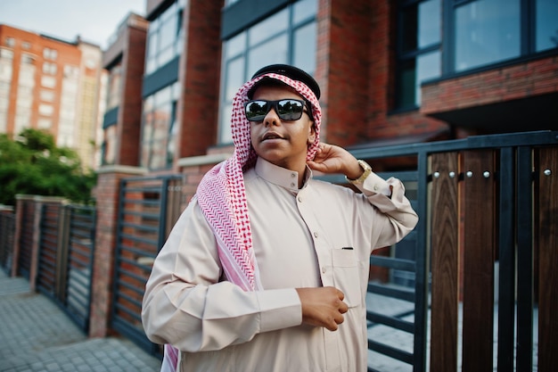 Ближневосточный арабский бизнесмен позирует на улице на фоне современного здания в солнечных очках