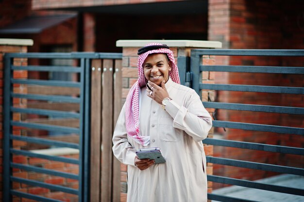 Middle Eastern arab man posed on street against modern building with tablet at hands