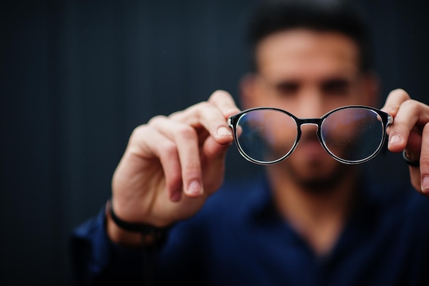 Free photo middle eastern entrepreneur wear blue shirt show close up eyeglasses against steel wall