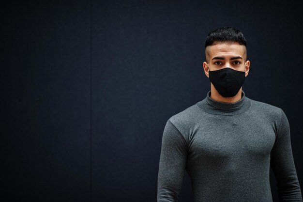 Middle eastern man in gray turtleneck and black face protect mask on isolated background