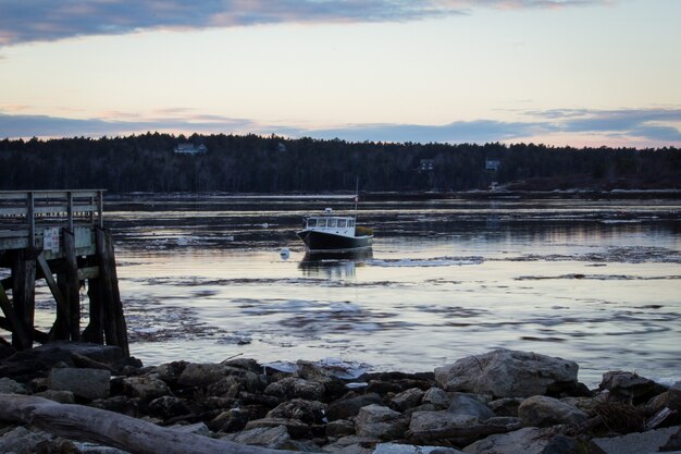 夕暮れ前に岩のビーチに近い海の海岸でクルージングする中型の漁船