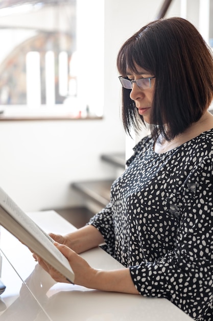 Free photo a middleaged brunette woman in glasses with a bob haircut is reading a book
