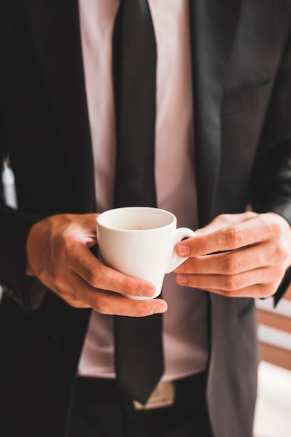 Midsection of businessman holding coffee cup