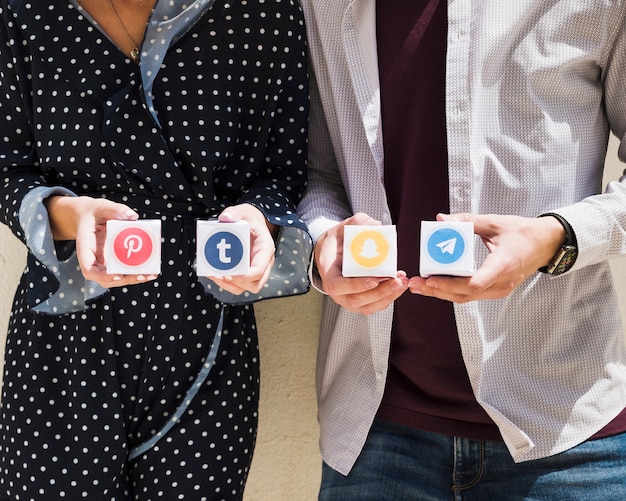 Midsection of a couple holding boxes of social media icons