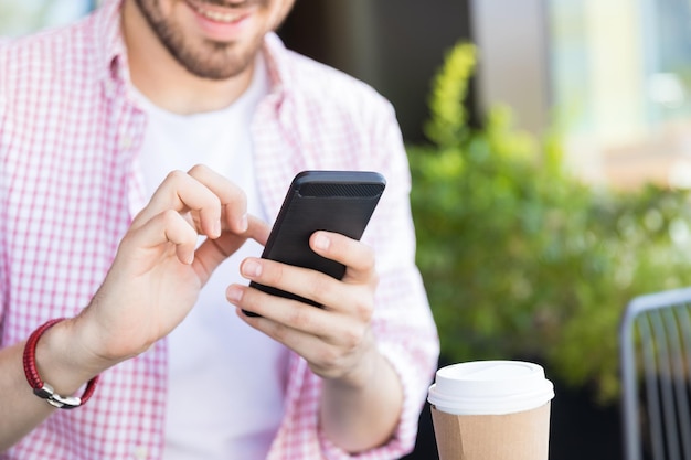 Midsection of Hispanic influencer scrolling messages on smartphone at cafe