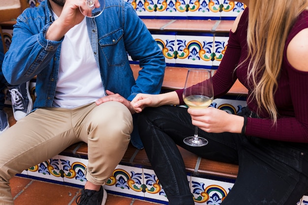 Midsection of loving couple on staircase holding glass of alcohol