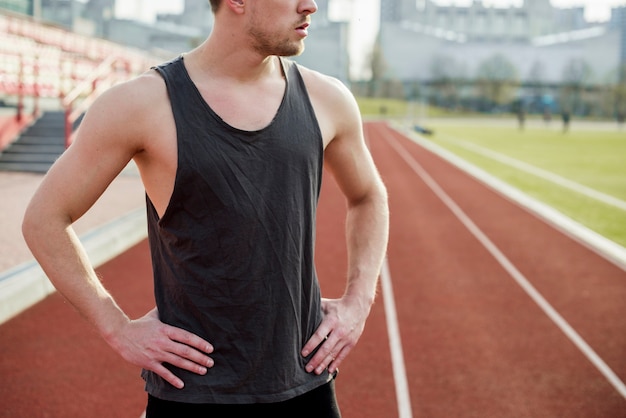 Midsection of a male athlete standing on the race track