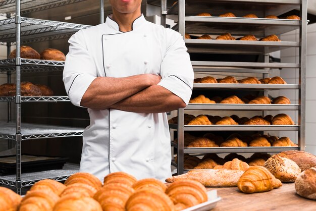 彼の腕を持つ男性のパン屋の中央部はパン屋で立っている交差