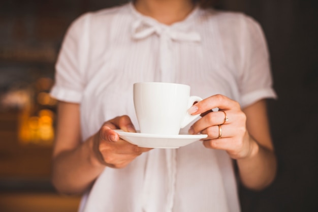 無料写真 レストランに立っている間コーヒーカップを保持している女性の中央部