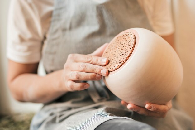 Midsection; of a skilled potter holding ceramic pot in hand