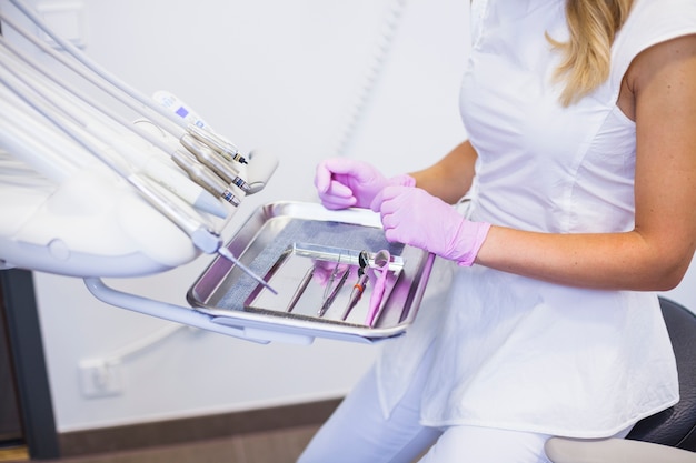 Midsection view of a dentist's hand arranging dental tools on tray