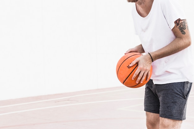 Midsection view of a male player's hand holding basketball