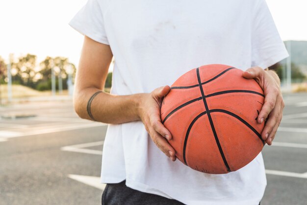 Midsection view of a man holding basketball