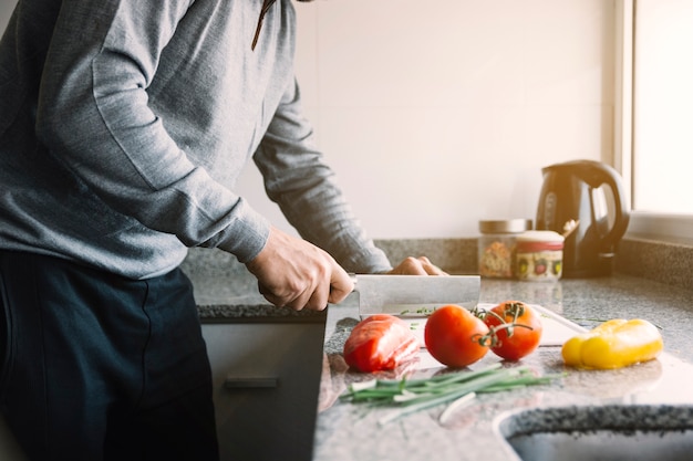 Foto gratuita vista del midsection della verdura di taglio manuale di un uomo in cucina