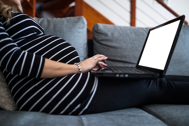 Midsection view of pregnant woman using laptop