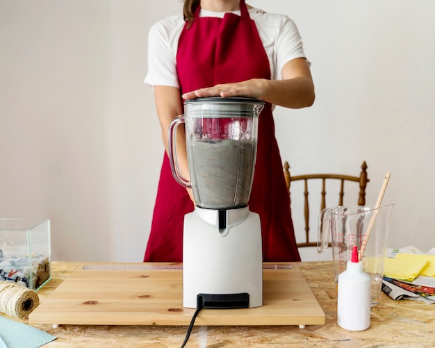 Free photo midsection view of a woman grinding paper pulp in mixer